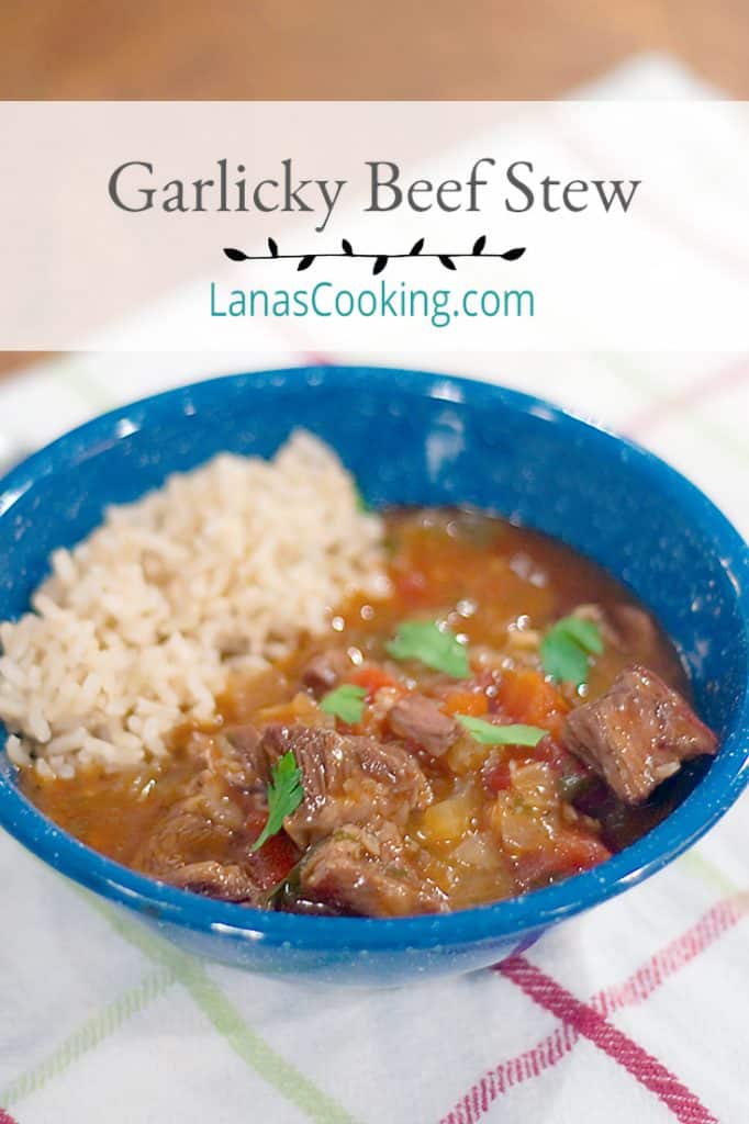 A serving of Garlicky Beef Stew over brown rice in a blue bowl. Text overlay: Garlicky Beef Stew, lanascooking.com