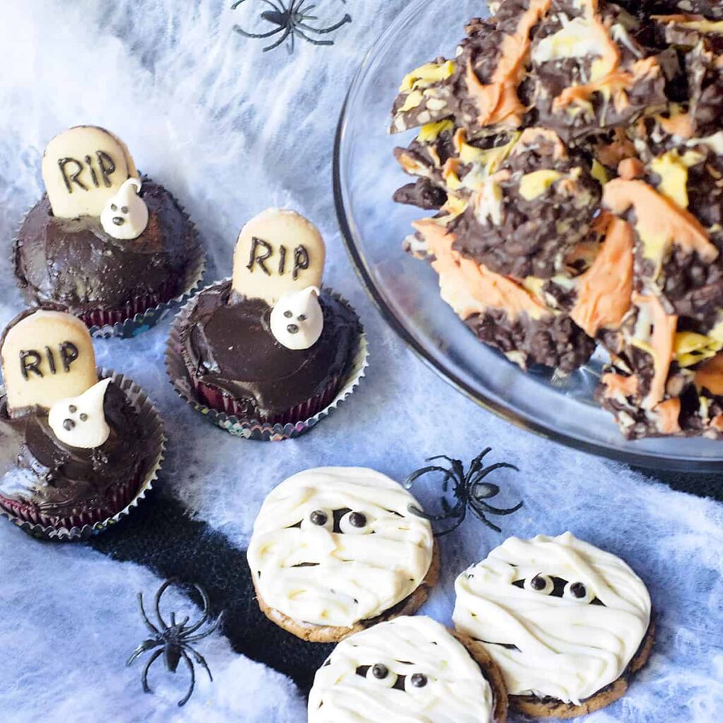 Ghosts in the Graveyard cupcakes, Mummy Cookies, and Candy Corn Bark on a spiderweb background.