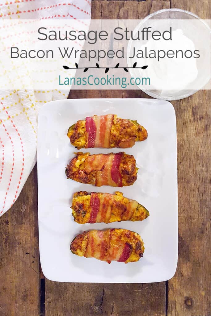 Sausage stuffed bacon wrapped jalapenos on a white serving plate.