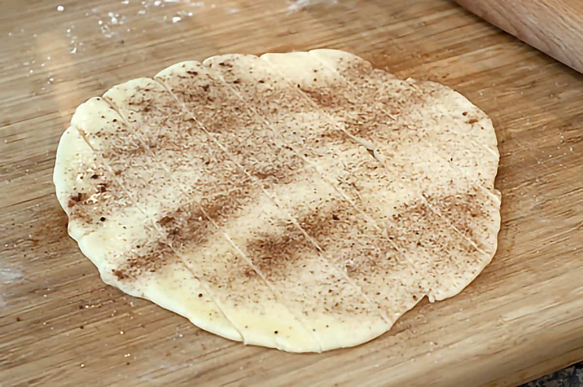 Pie crust sprinkled with cinnamon and sugar on a cutting board.