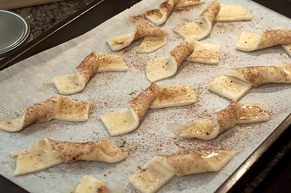 Pie crust strips twisted and sprinkled with cinnamon sugar on a baking sheet.