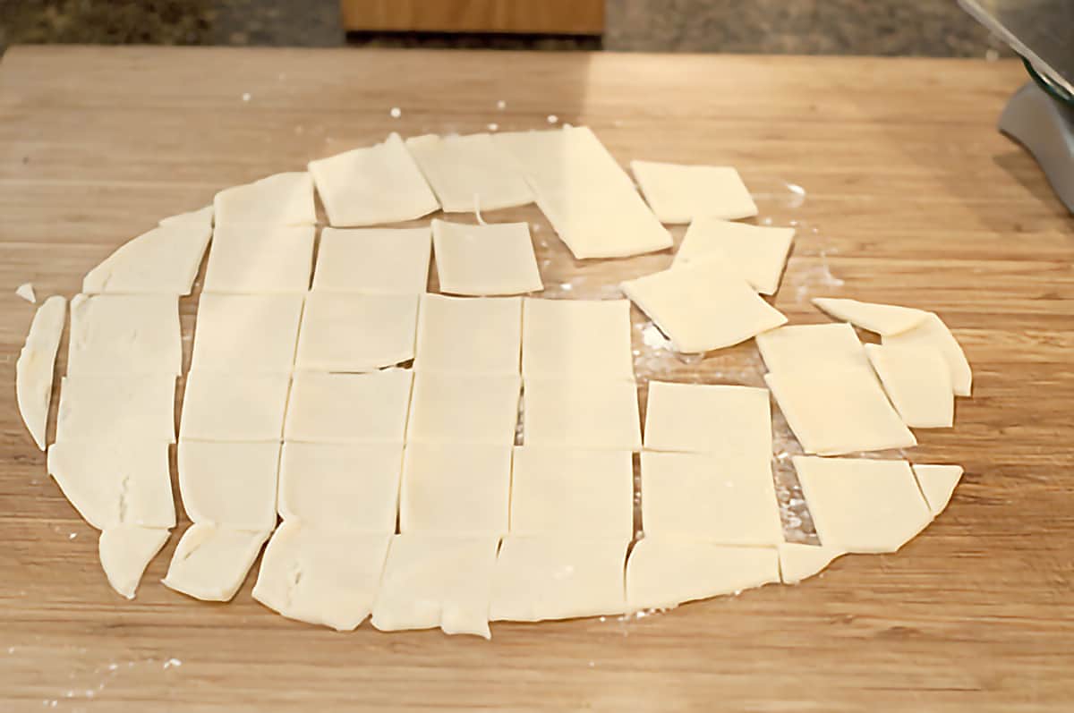 Pie crust cut into squares on a cutting board.