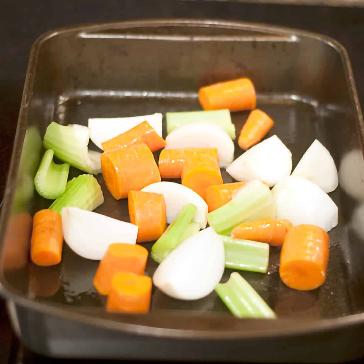 Aromatics for stuffed pork loin A baking pan containing carrots, onions, and celery.
