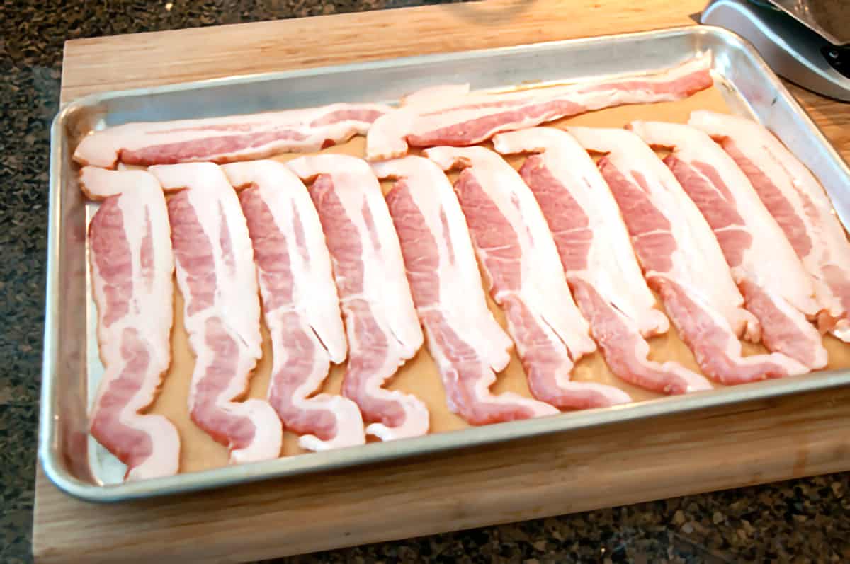 Slices of bacon on a baking sheet.
