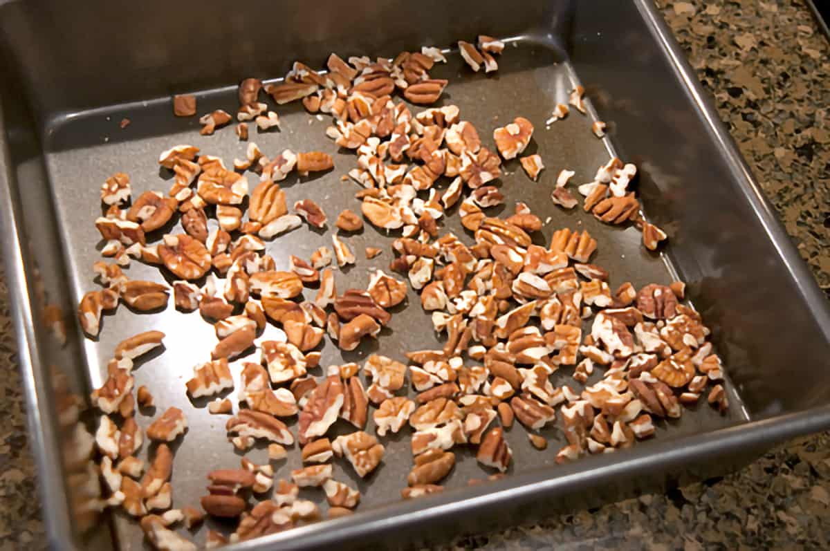 Chopped toasted pecans in a baking pan.