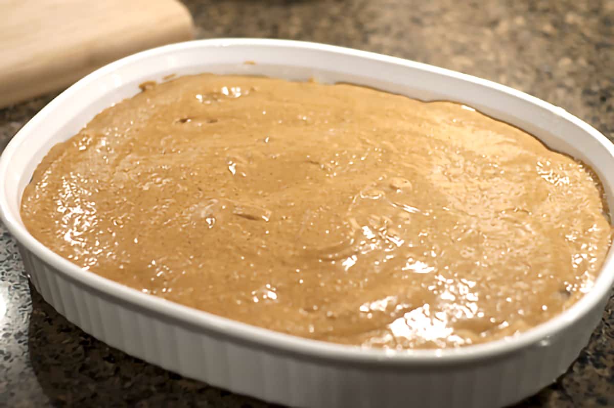 Baking dish with gingerbread mixture poured on top of apple pie filling.