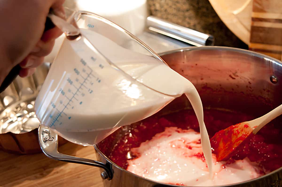 Add buttermilk to Polly's Pink Stuff Buttermilk being poured into cooled jello and pineapple mixture.