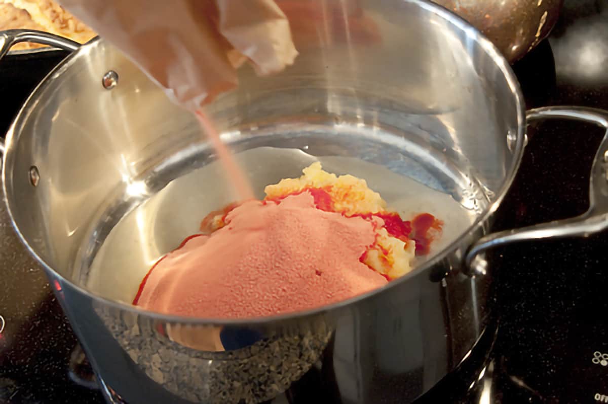 Raspberry jello and pineapple in a medium pot.