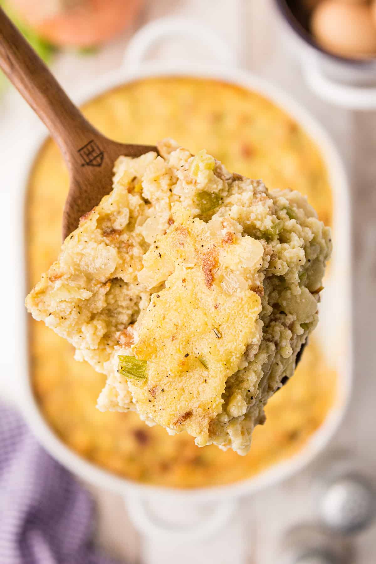 Closeup of a serving of Southern Cornbread Dressing with a white serving dish in the background.