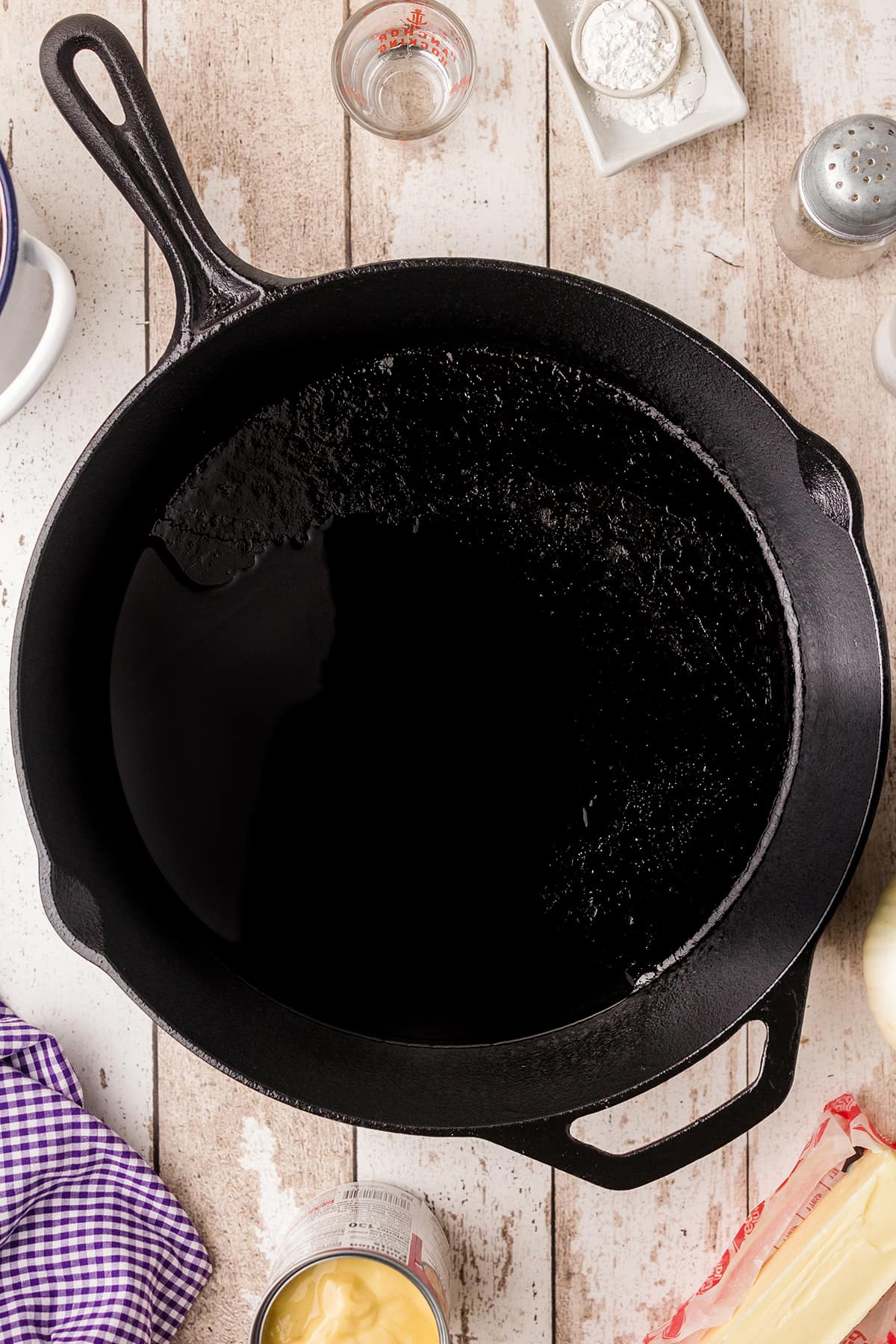 A black cast iron skillet containing the oil needed for cooking cornbread.