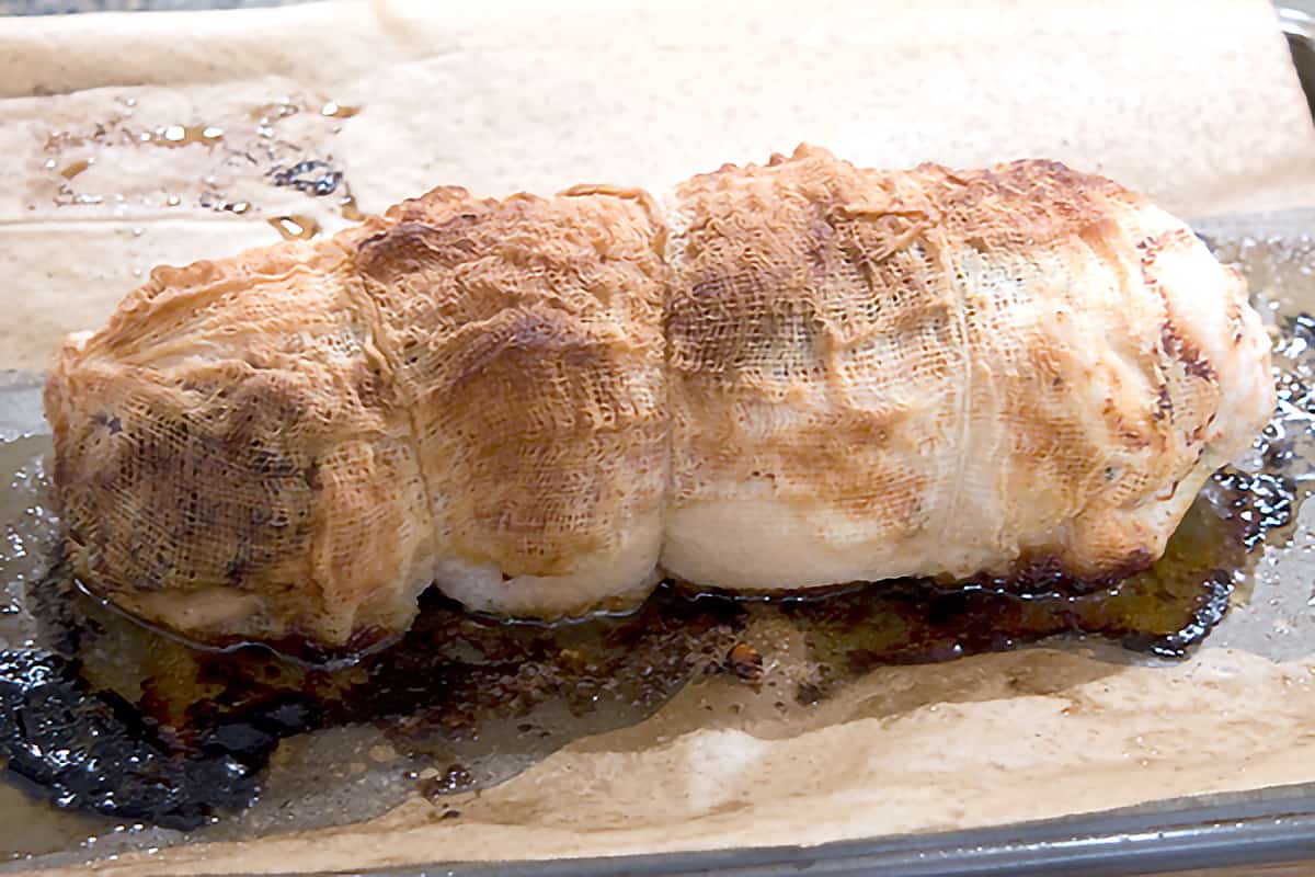 Cooked stuffed turkey breast on a baking sheet.