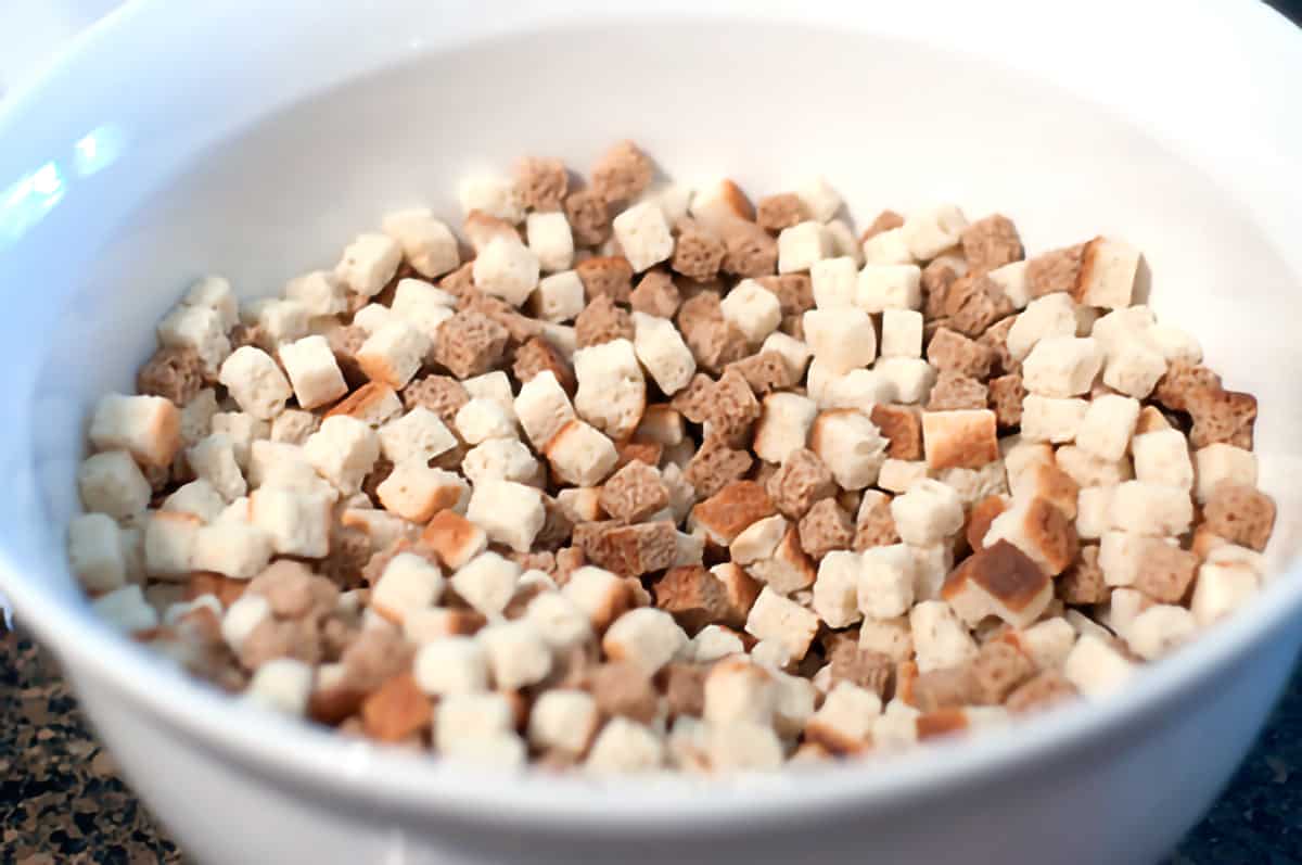 Large mixing bowl containing white and wheat bread cubes.