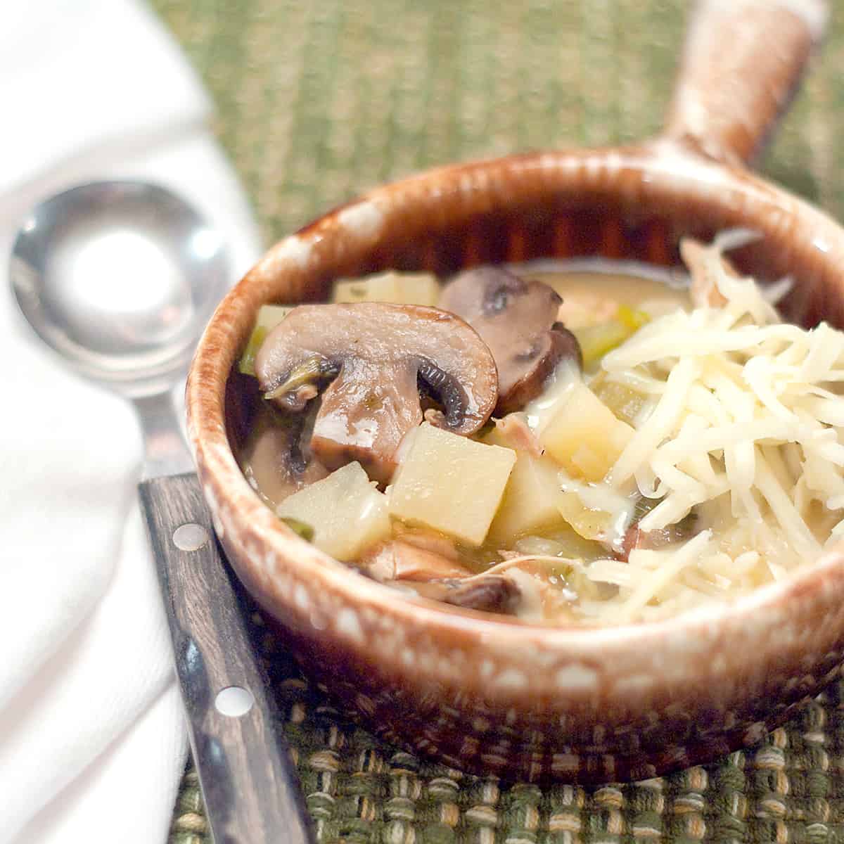 Leftover turkey soup in a vintage serving bowl with a spoon.