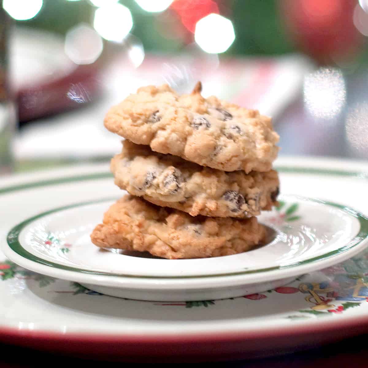 Almond Joy Cookies on a Christmas plate with twinkling lights in the background.