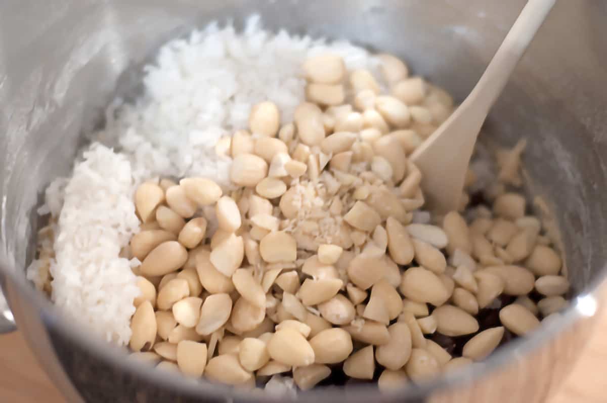 Ingredients for Almond Joy Cookies in a large mixing bowl with a wooden spoon.