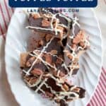 Plate of toffee topped with bacon, pecans, dark chocolate, and white chocolate drizzle on a striped cloth.