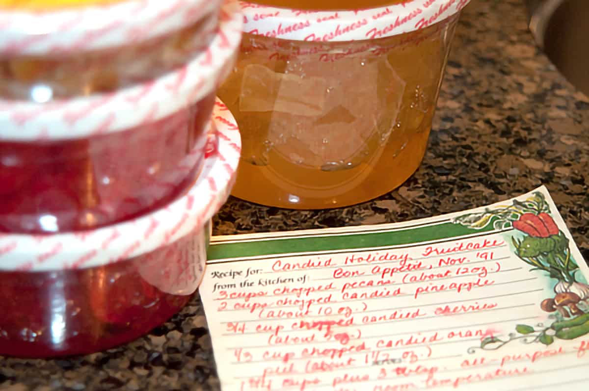 Candied Holiday Fruitcake Handwritten recipe card in the foreground with candied fruit in the background.