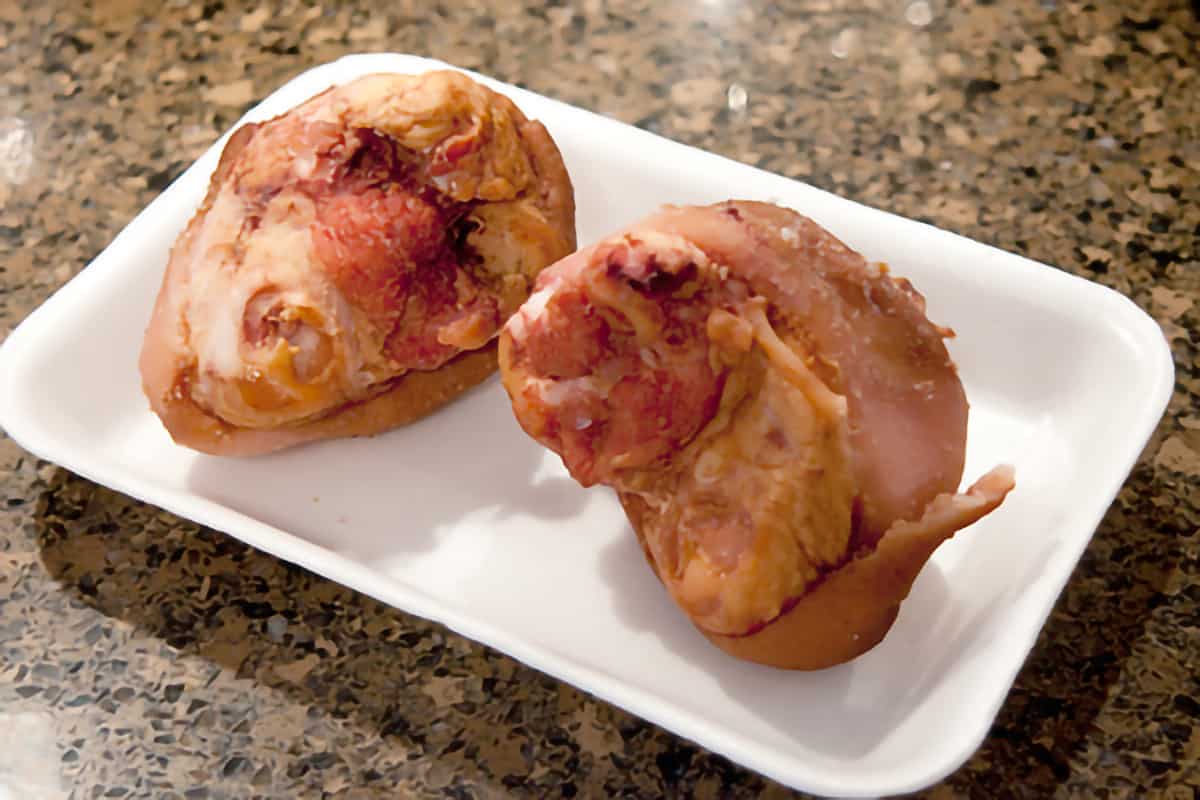 Two smoked ham hocks sitting on a plastic tray.