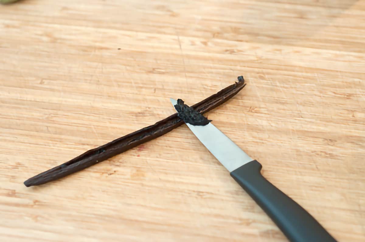 Small knife and a vanilla bean on a cutting board.