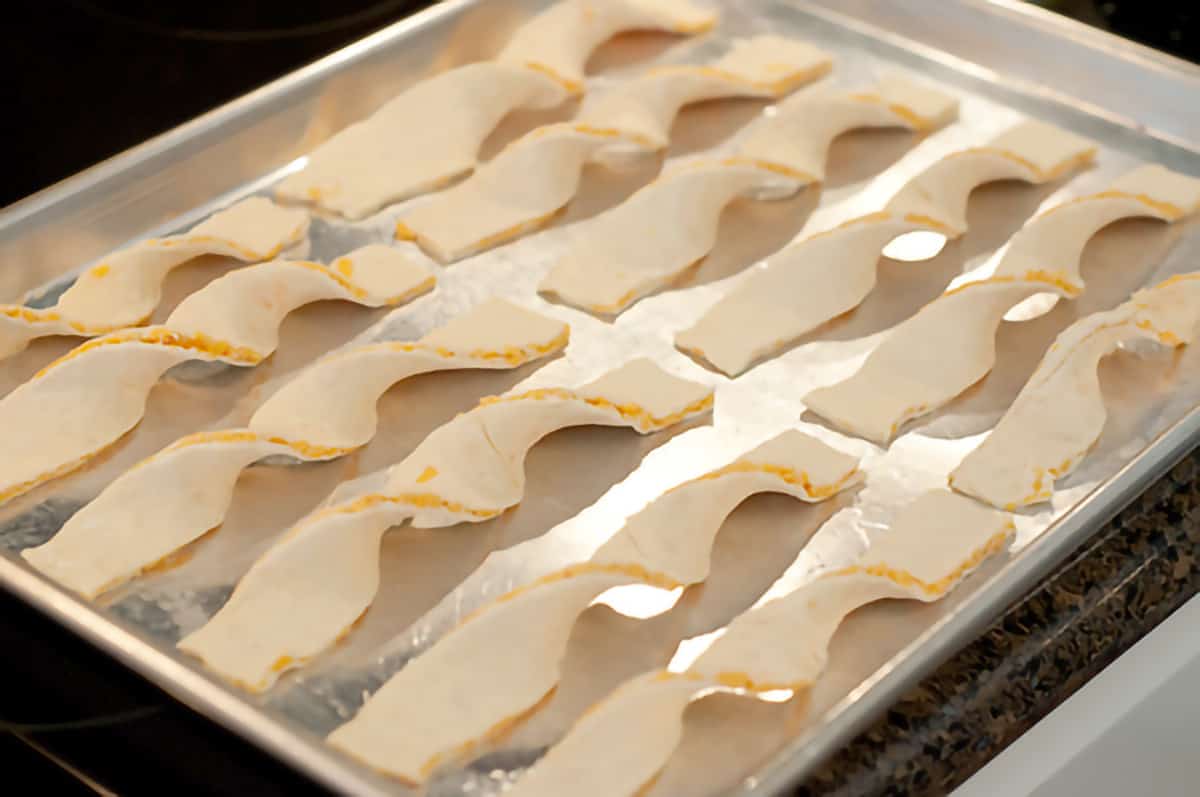 Twisted strips of puff pastry on a baking sheet.