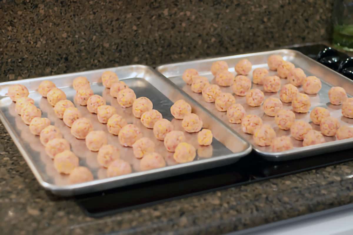 Sausage balls rolled out and lined up on baking sheets.