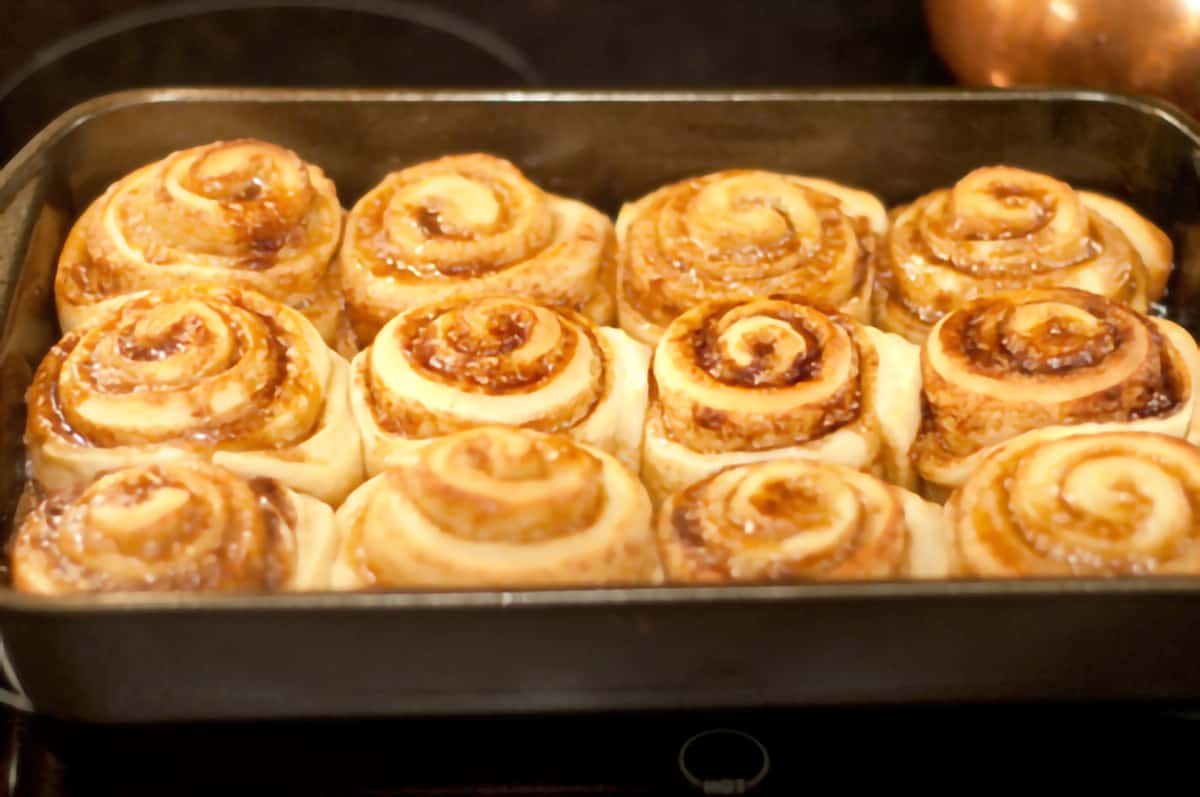 Baking pan with twelve baked cinnamon rolls.