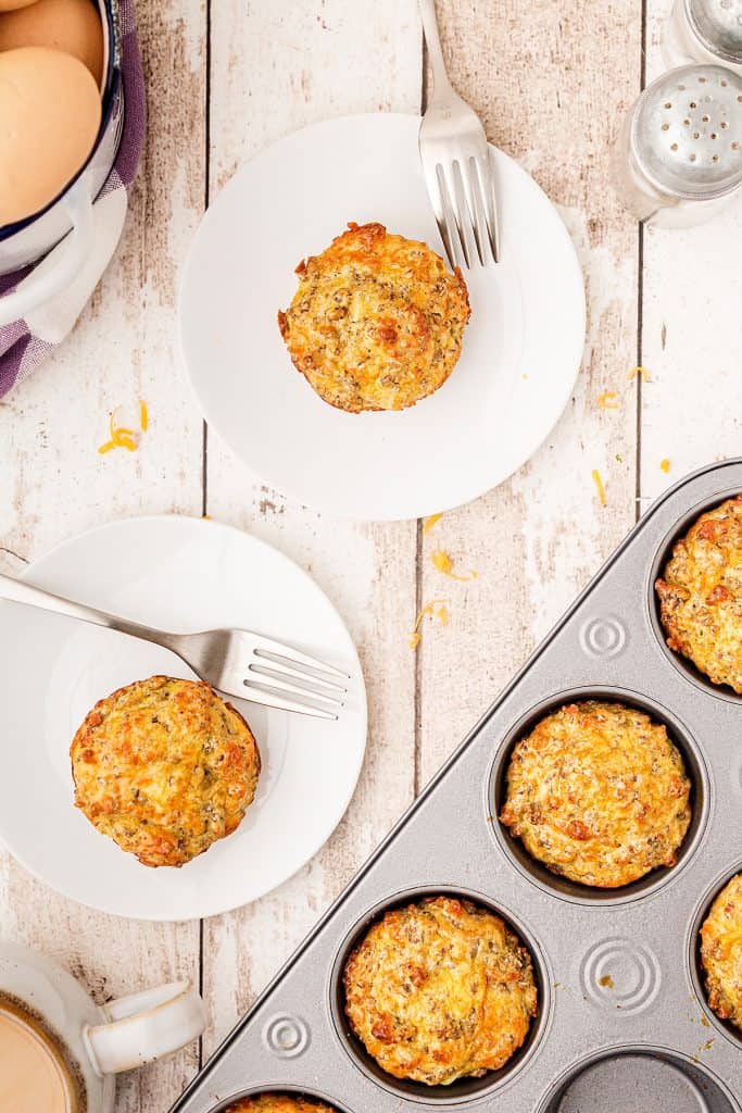 Servings of easy sausage muffins on white plates with a baking tray in the foreground.