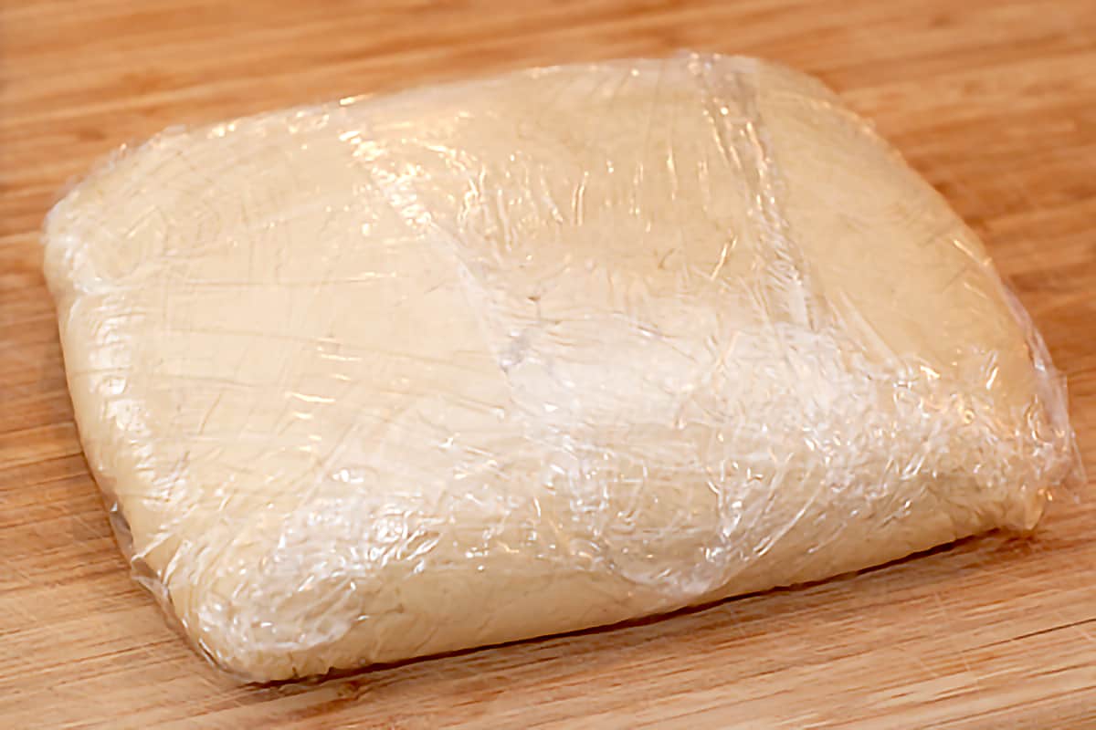 Finished dough shaped into a rectangle and wrapped in plastic wrap.
