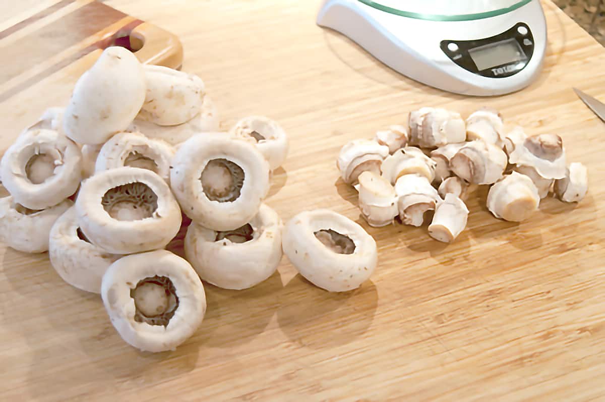 Mushroom caps and stems on a wooden cutting board.