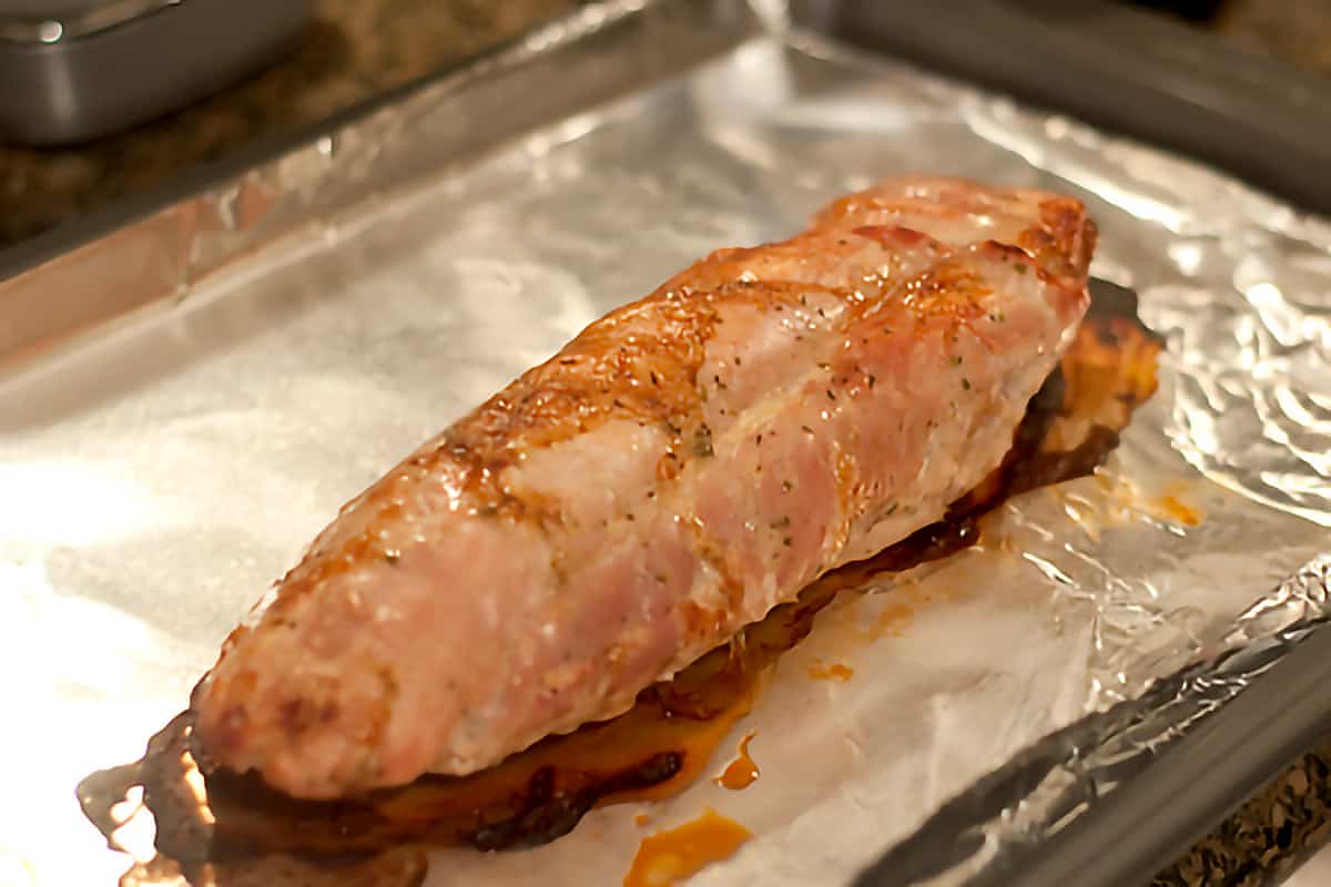 Cooked pork tenderloin on a shallow roasting pan.