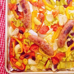 Baking sheet with cooked Italian sausage, onions, peppers, and tomatoes.