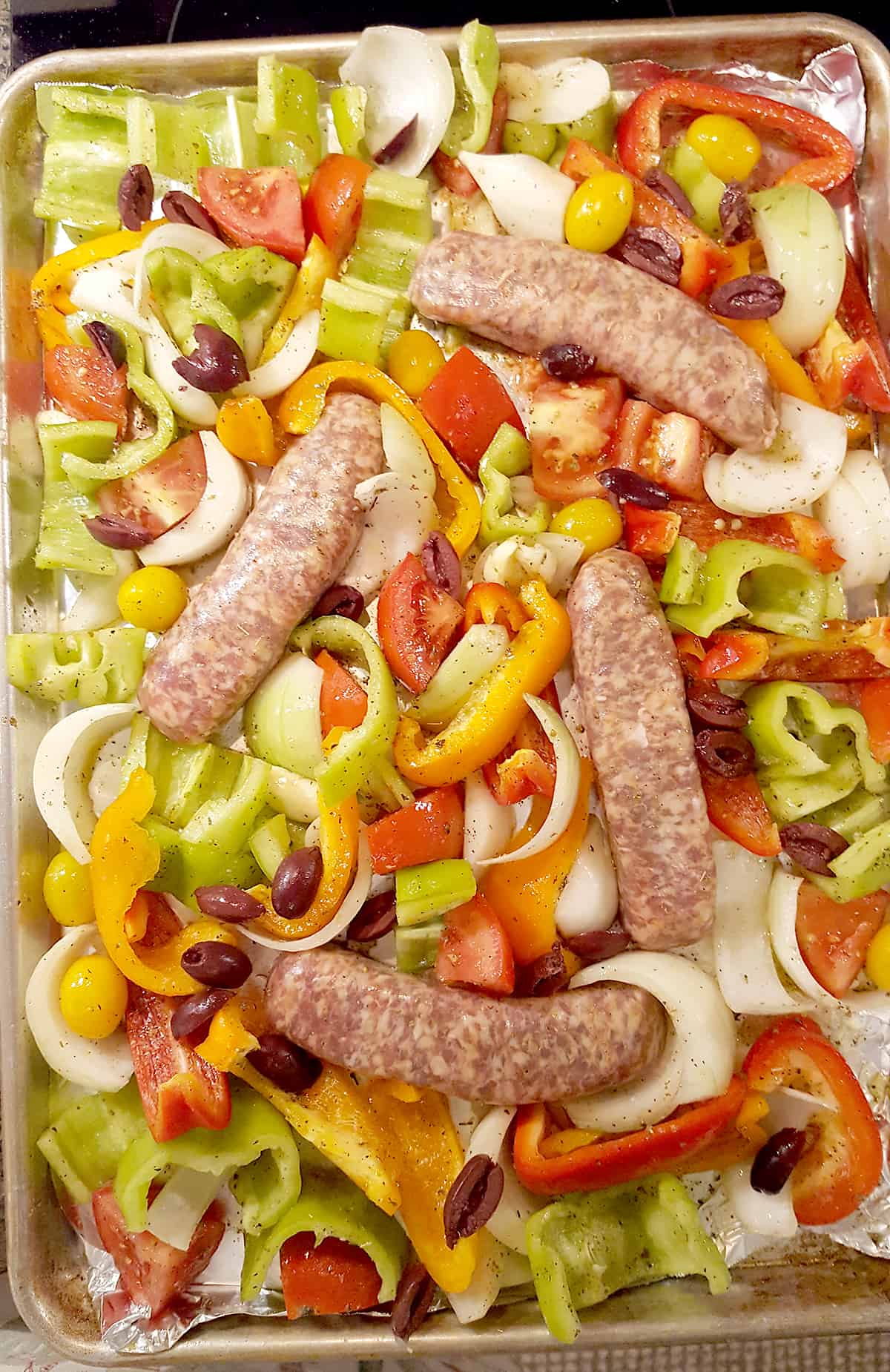 Half sheet pan with veggies and Italian sausage and olives added.