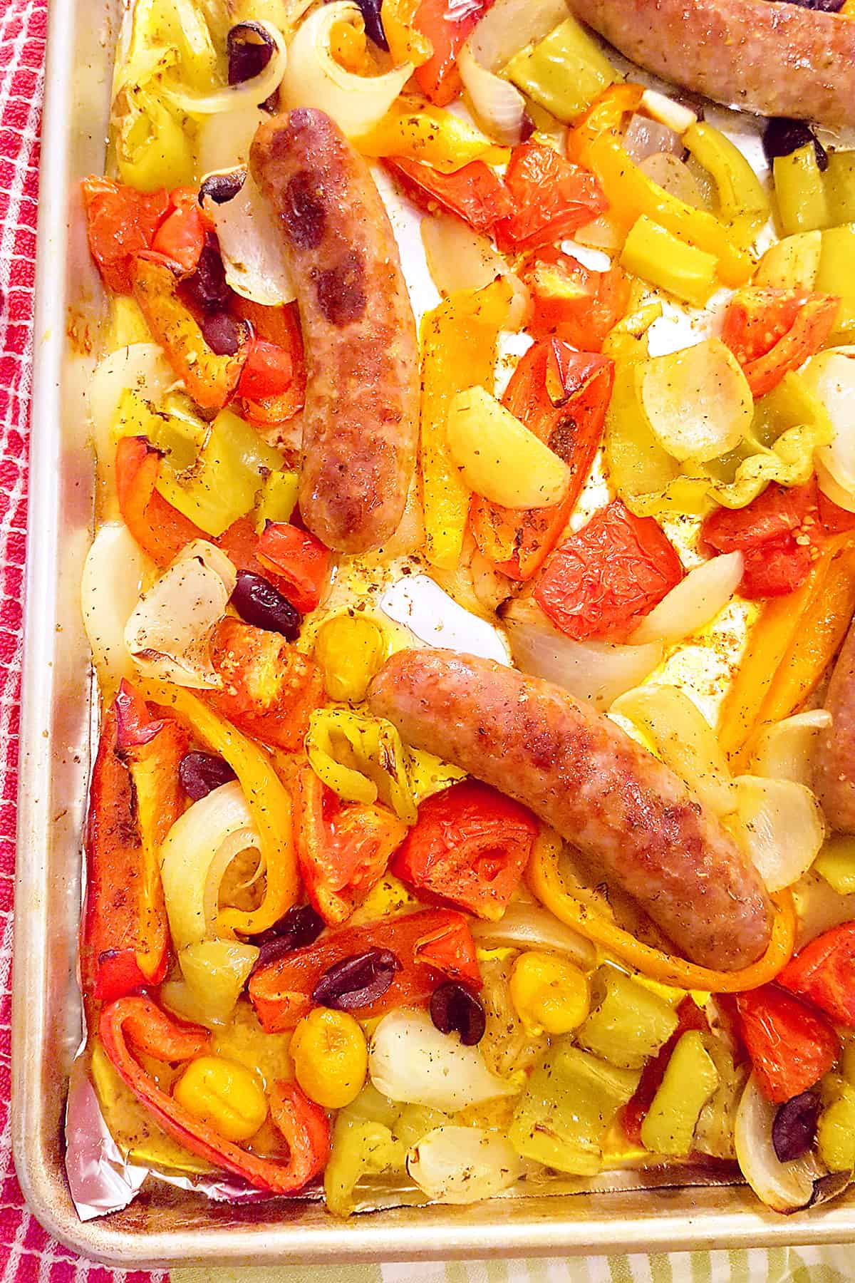 Sheet pan with veggies and sausages after cooking.