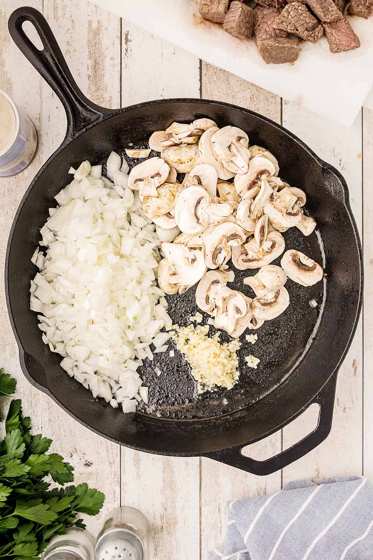 Onions, mushrooms, and garlic in black cast iron skillet.
