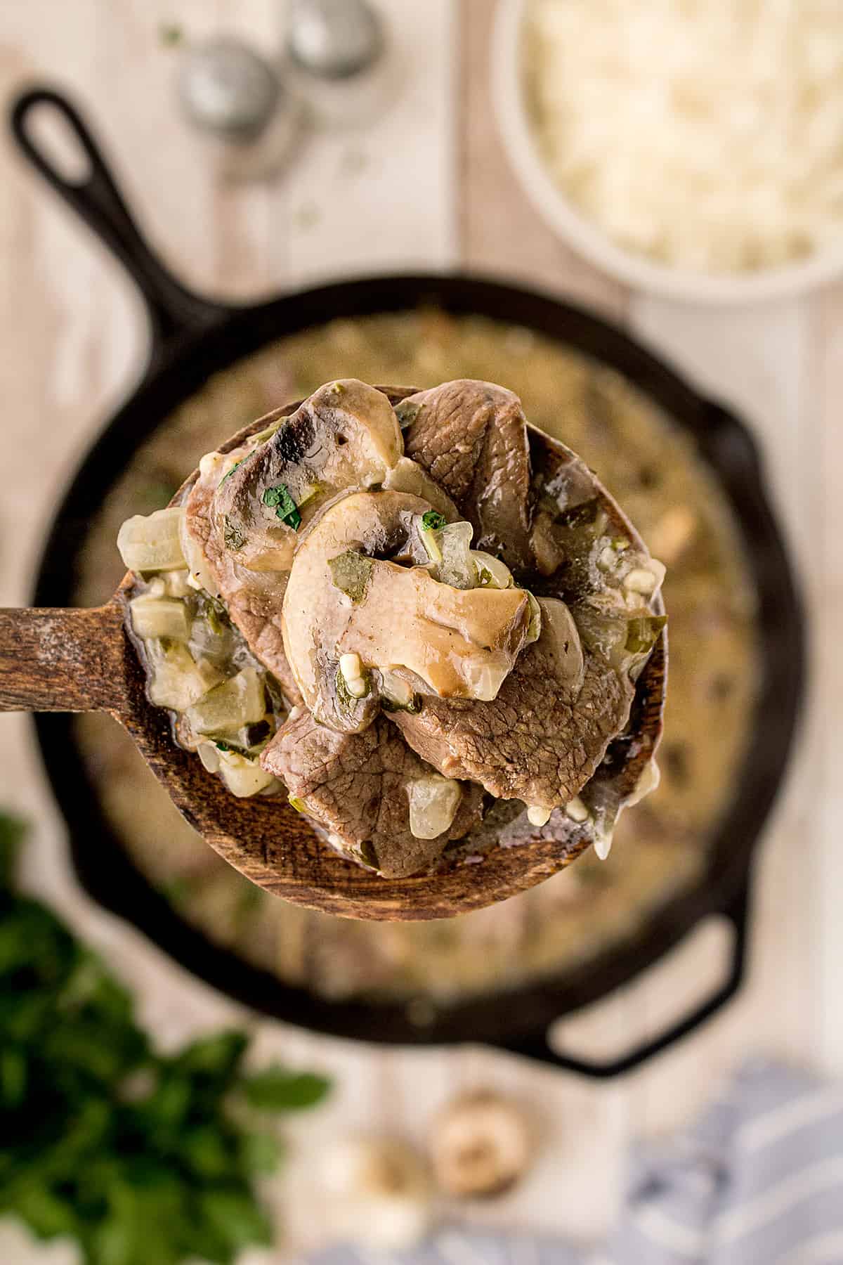 Wooden spoon holding a serving of Steak Tips with Creamy Mushroom Sauce.