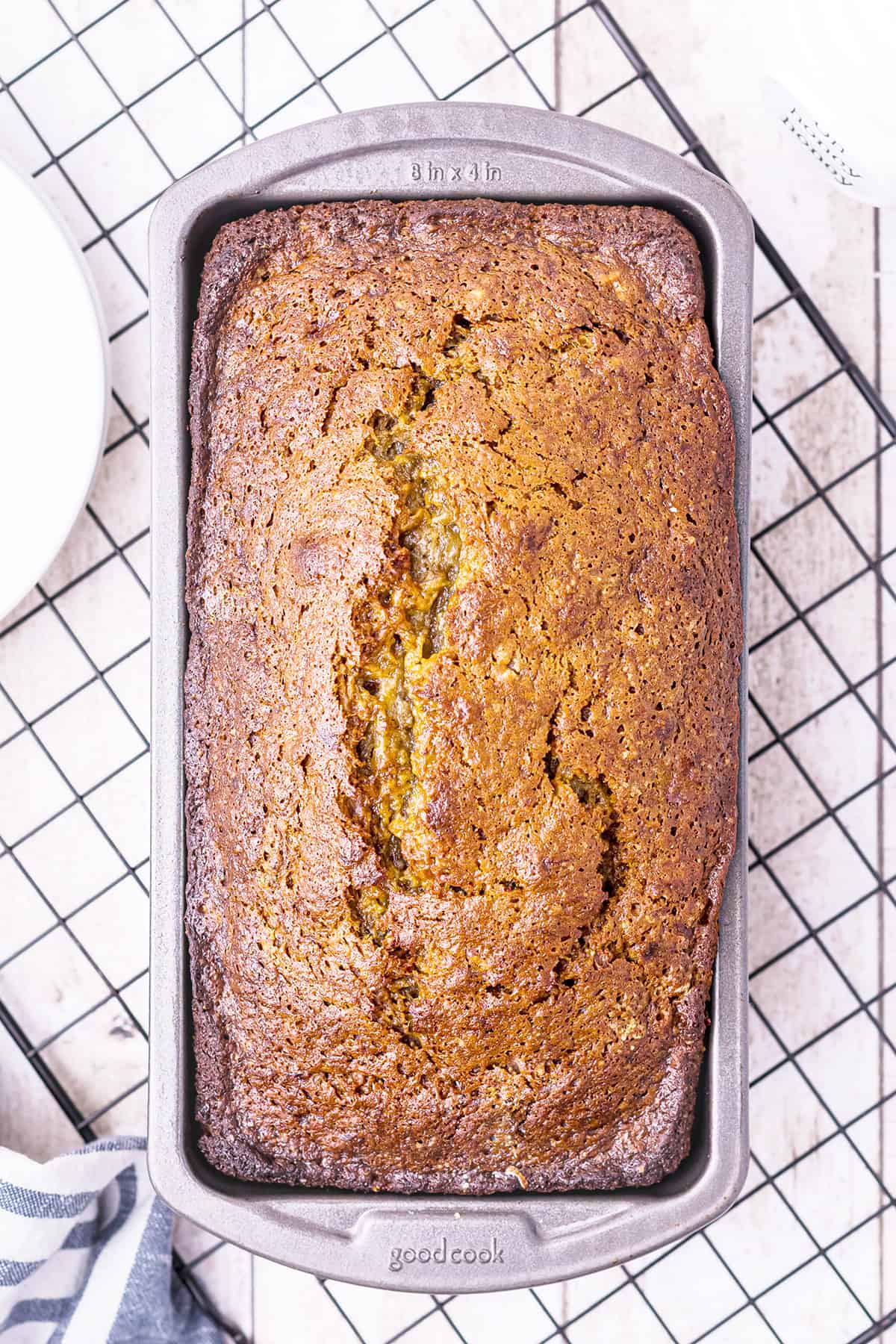 Baked banana nut bread in loaf pan on a cooling rack.