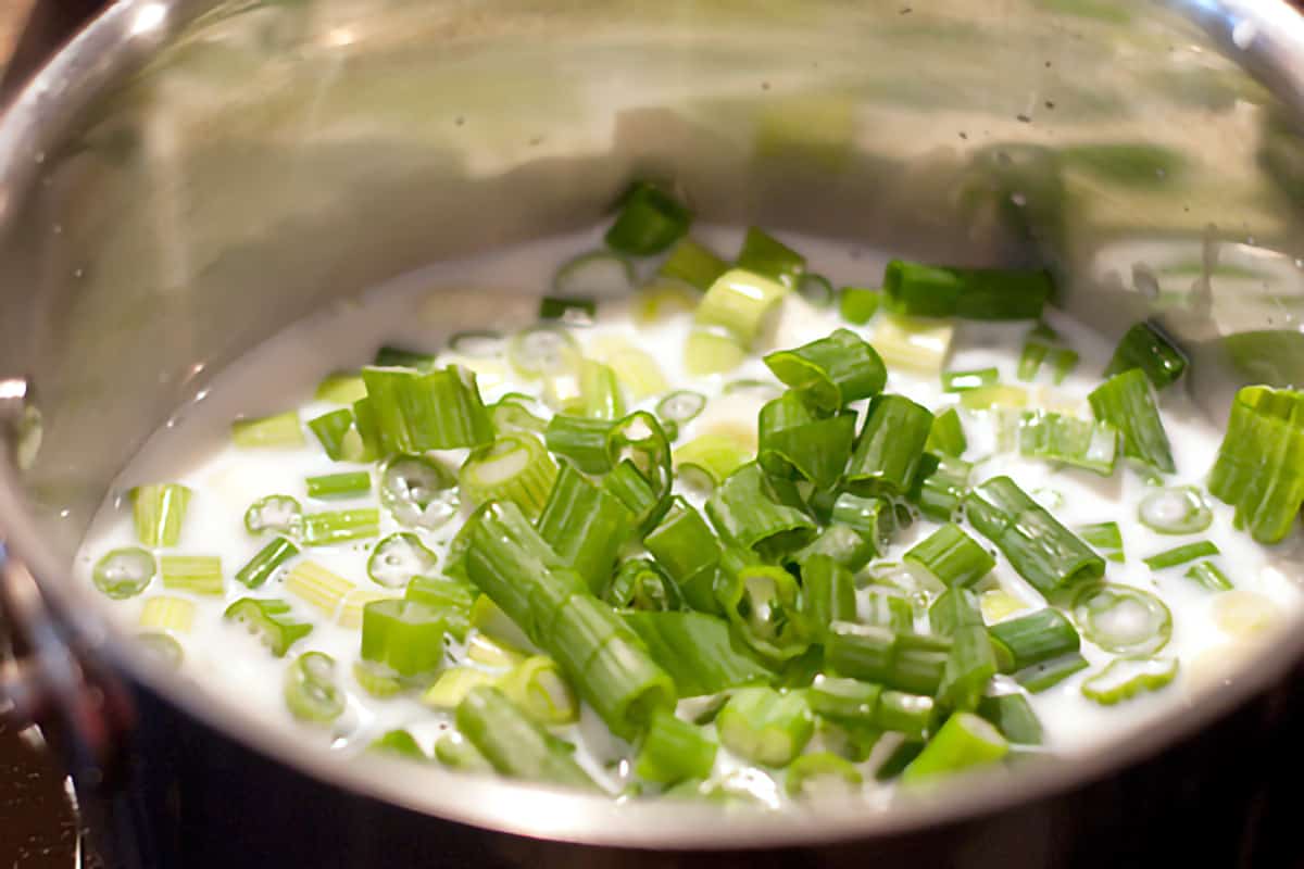 Milk and scallions simmering in a small pot.