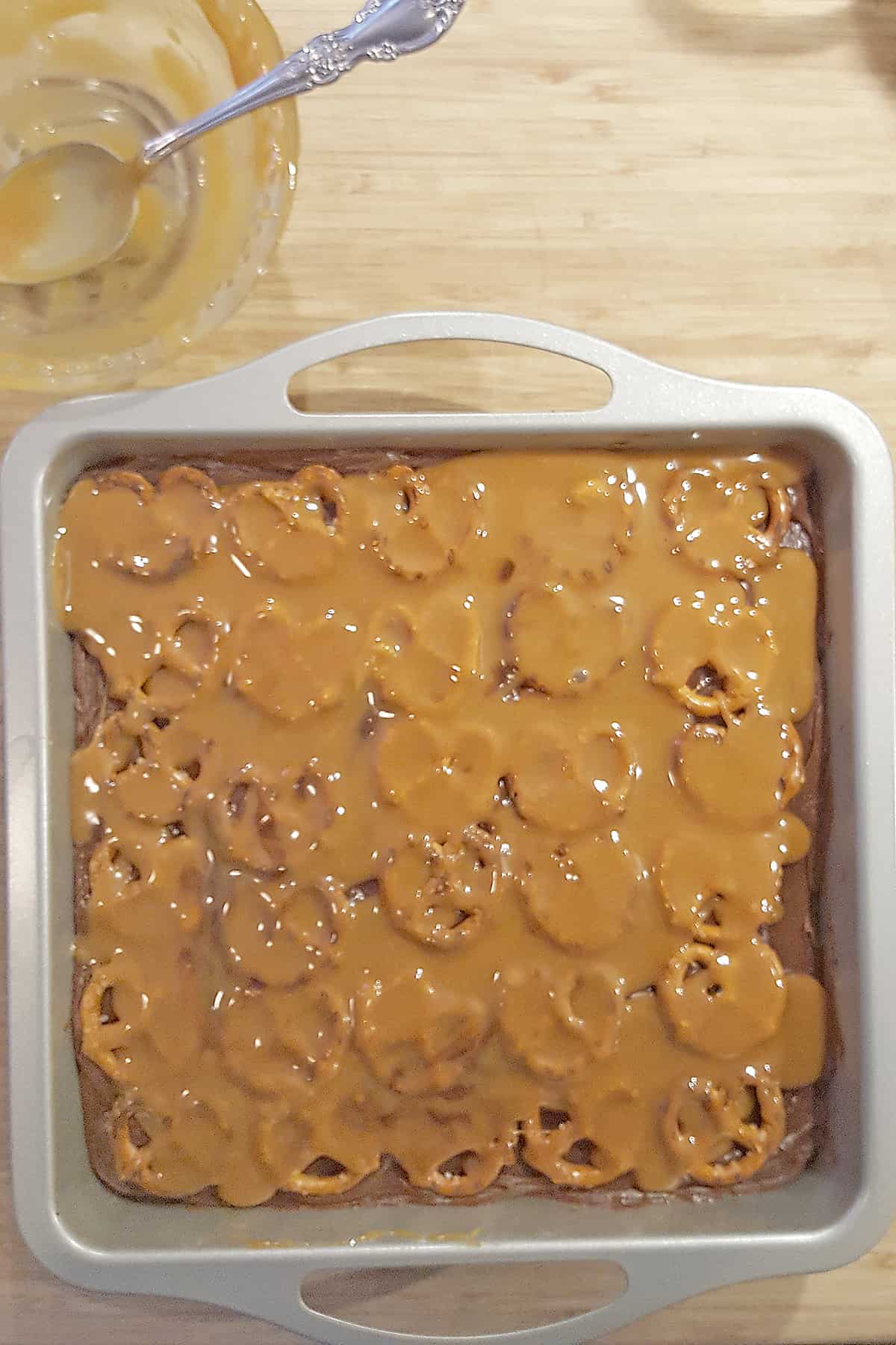 Brownies, milk chocolate frosting, and pretzels with a layer of melted caramel drizzled over.