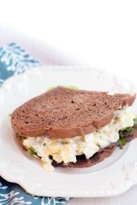Egg salad sandwich on a white plate.