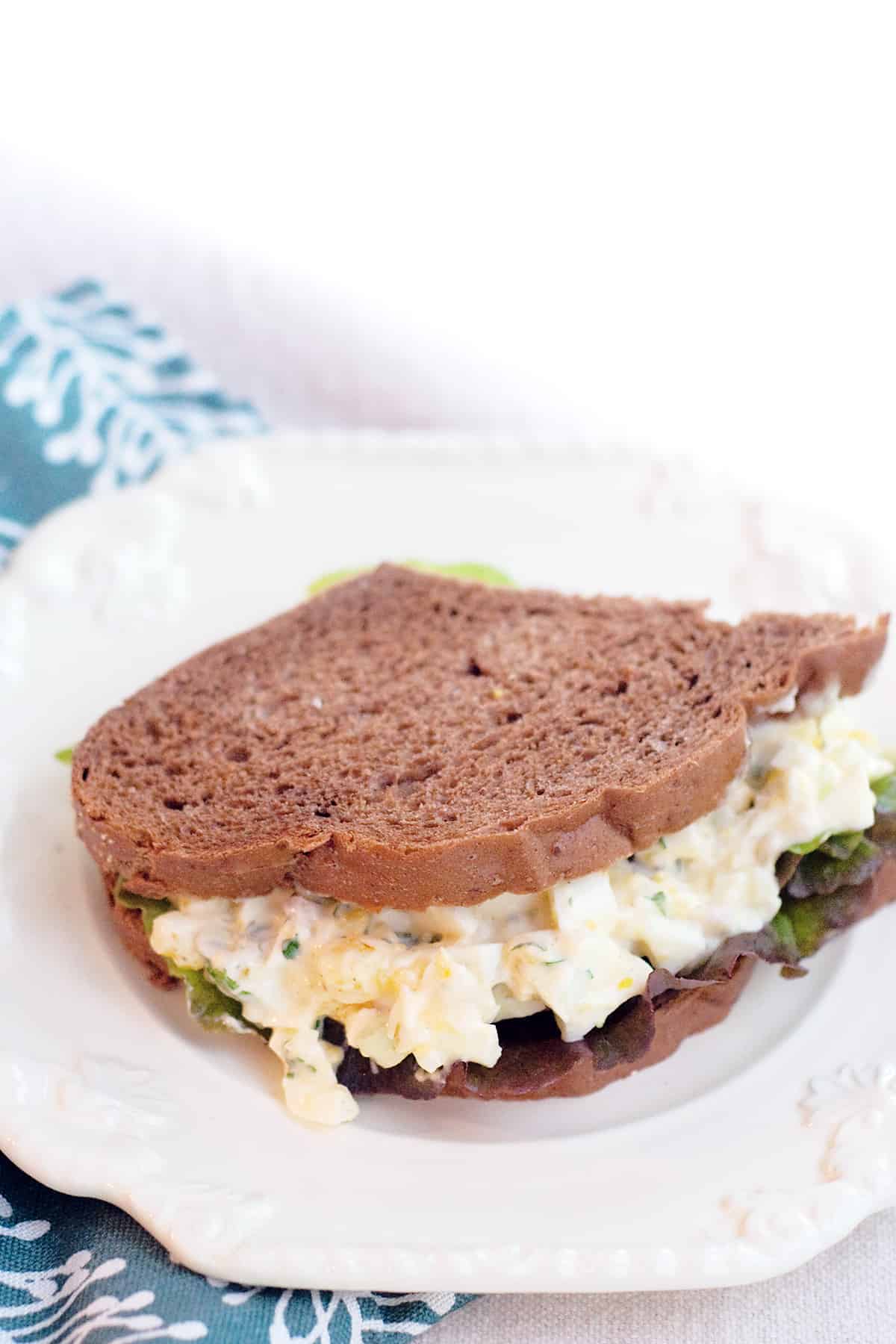 Herbed egg salad sandwich on a white serving plate.