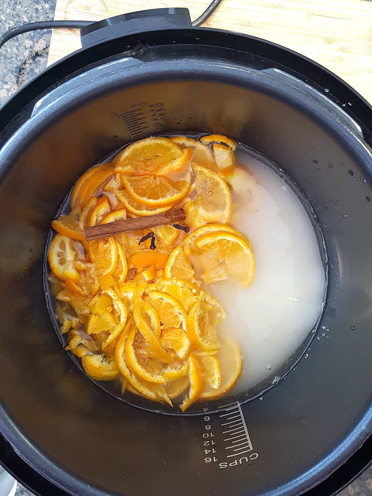 Oranges, sugar, water, and spices inside the pressure cooker.