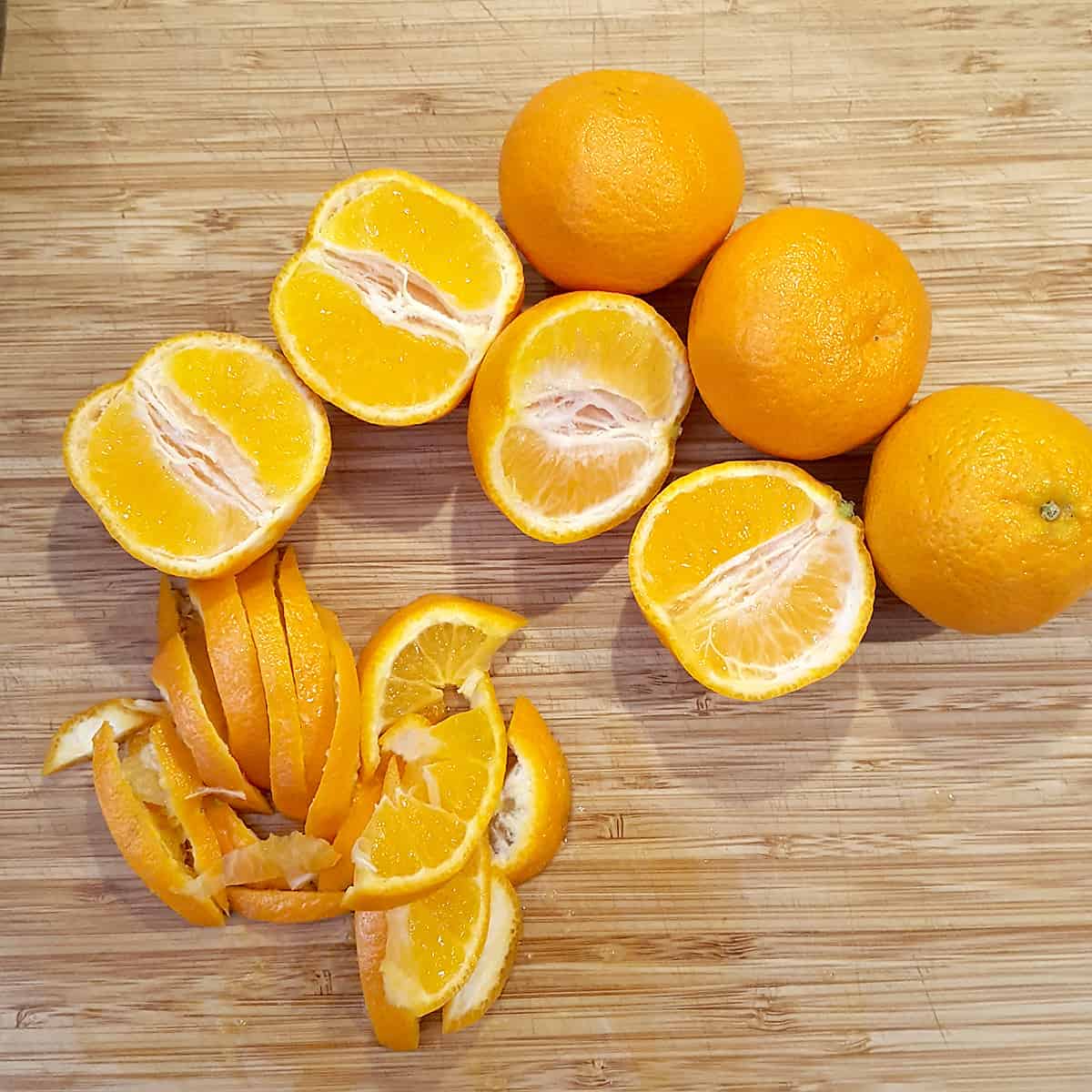 Mandarin oranges whole and sliced on a cutting board.