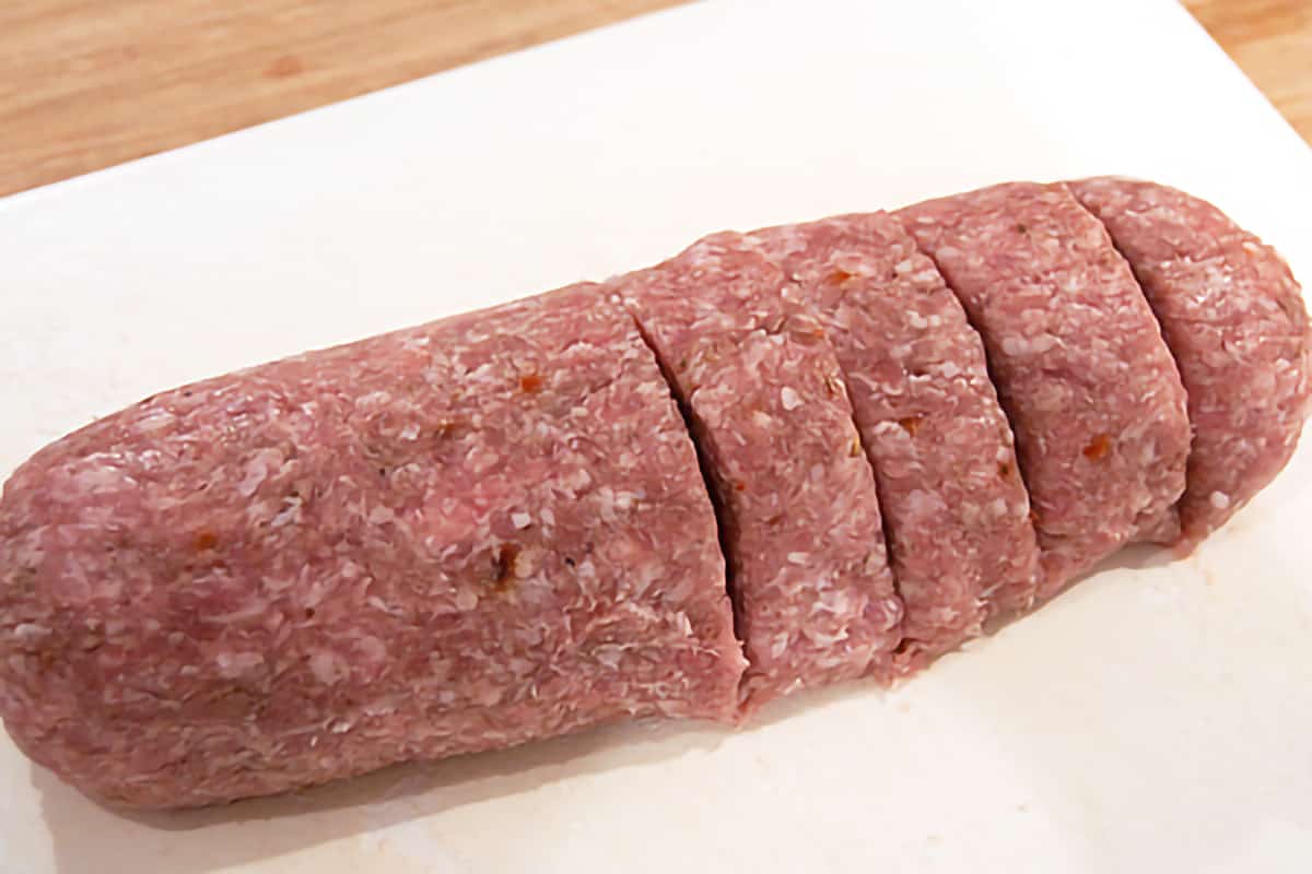 Sausage roll on a cutting board being sliced into 8 pieces.