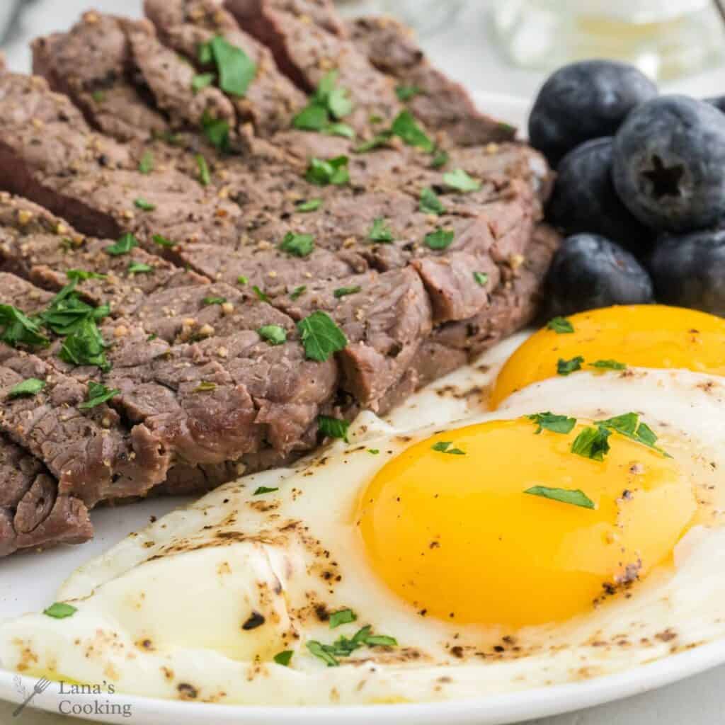 A serving of steak and eggs with parsley garnish.