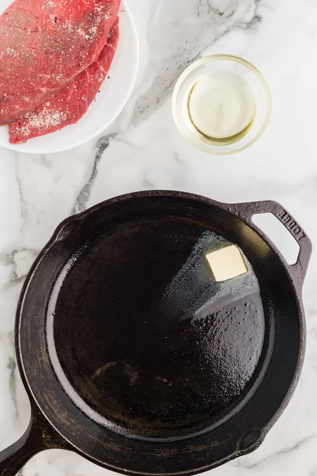 A cast iron pan with butter inside being melted.