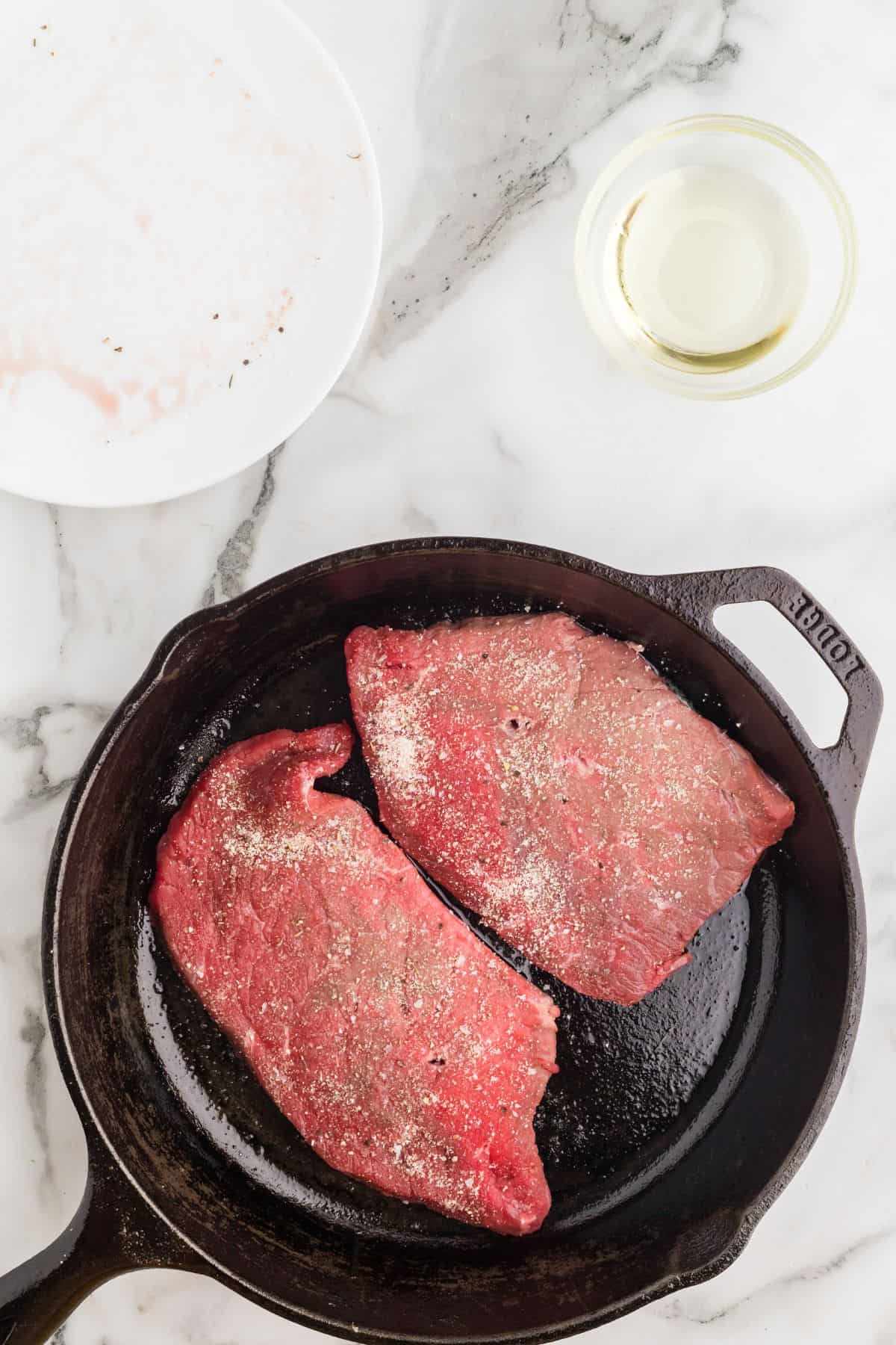 Into the preheated pan, the seasoned steaks are added to cook.
