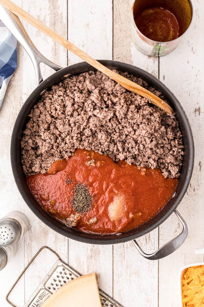 Spaghetti sauce, salt and pepper added to ground beef in skillet.