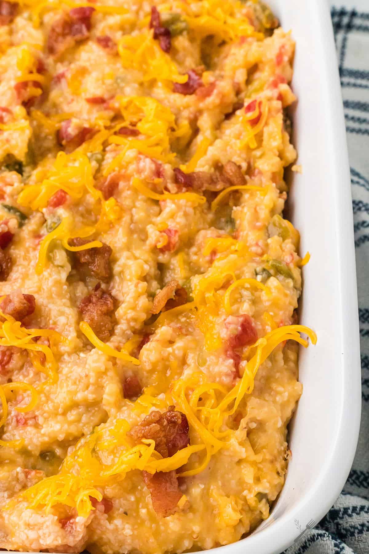 Cheessy tomato grits in a white baking dish.