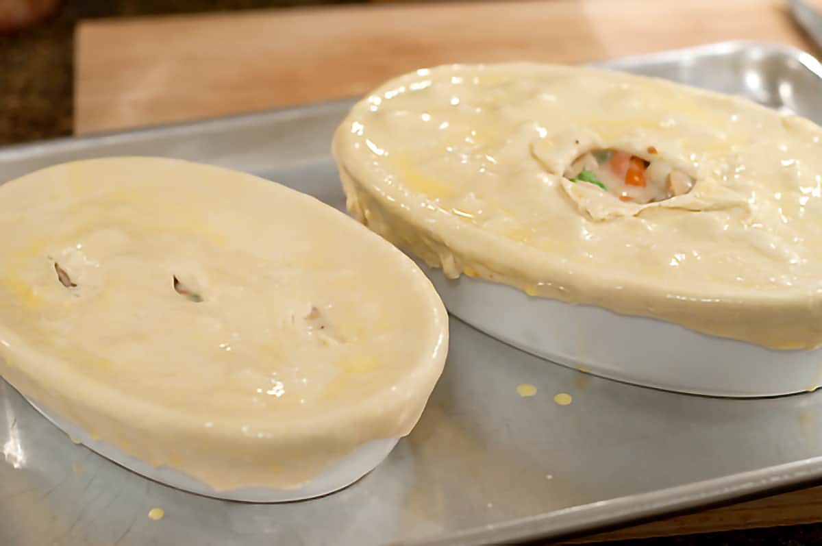 Filled and topped pot pies brushed with egg wash sitting on a baking sheet.