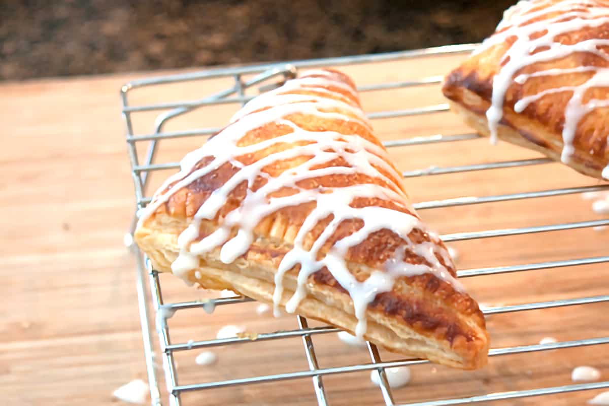 A finished pastry on a cooling rack drizzled with glaze.